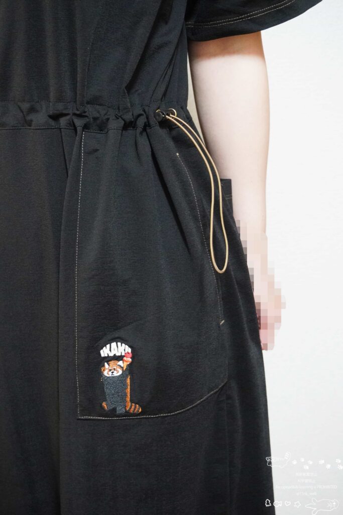 ウエストに絞り紐が付いた黒のワンピース。ポケットにアイスを掲げてイカクするレッサーパンダの刺繍が入っている